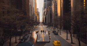 Photo/Vidéo : Main tenant un smartphone affichant des cyclistes sur une rue de New York, immeubles en arrière-plan.